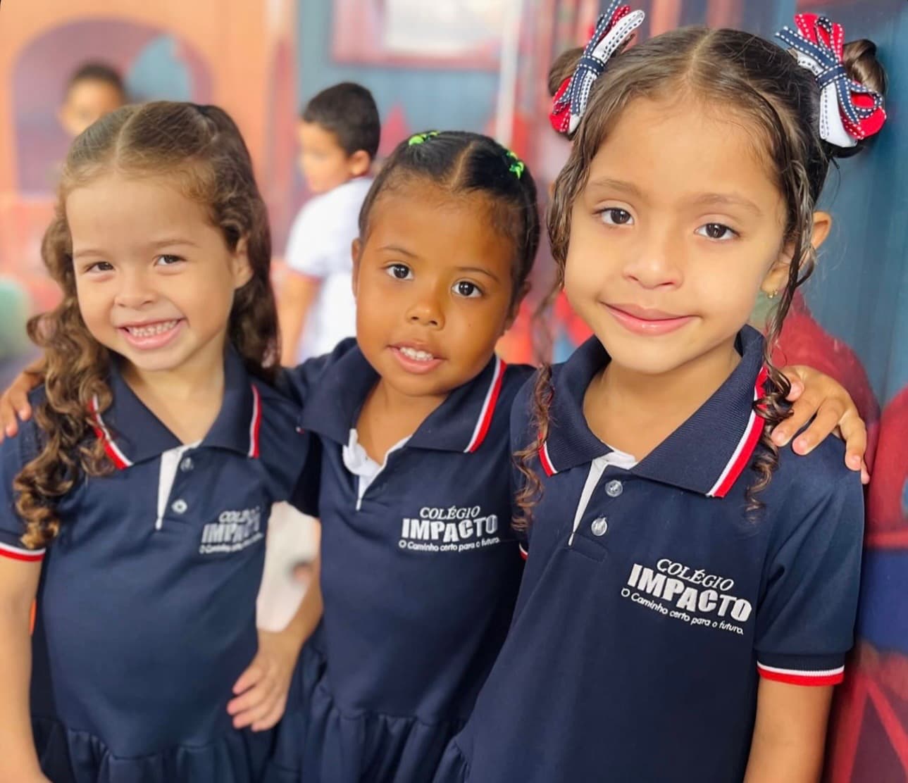 Três alunas da Educação Infantil do Colégio Impacto sorrindo abraçadas