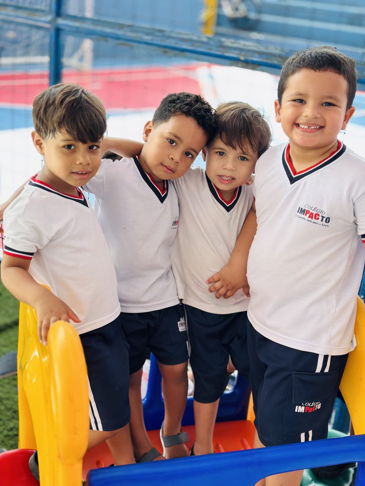 Alunos do Colégio Impacto sorrindo, vestindo o uniforme da escola